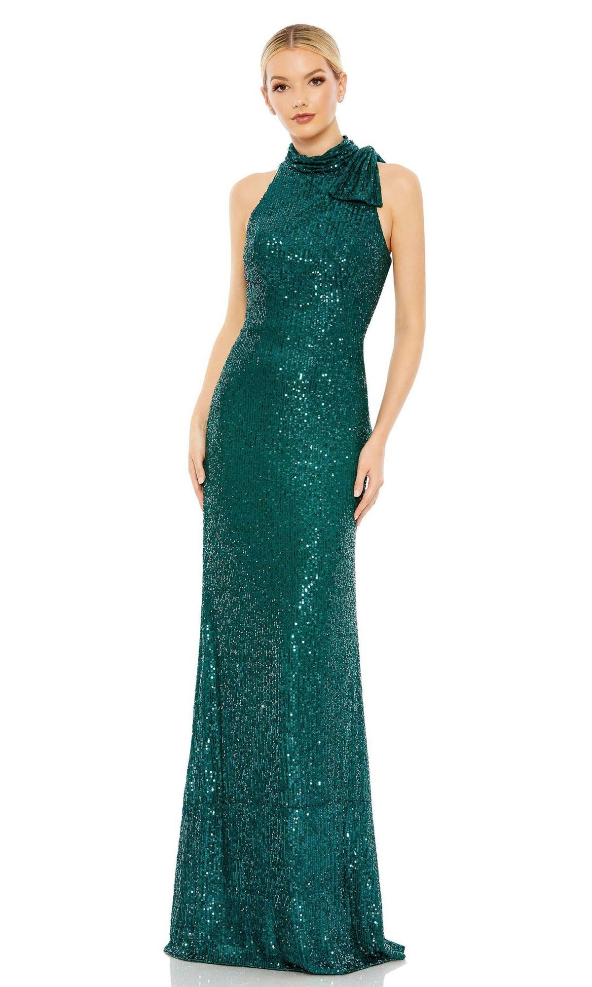 A woman wears the Mac Duggal 11280 Bow Long Sequin Formal Dress—an emerald green, floor-length, sleeveless gown with a high neckline and a bow detail on one shoulder.
